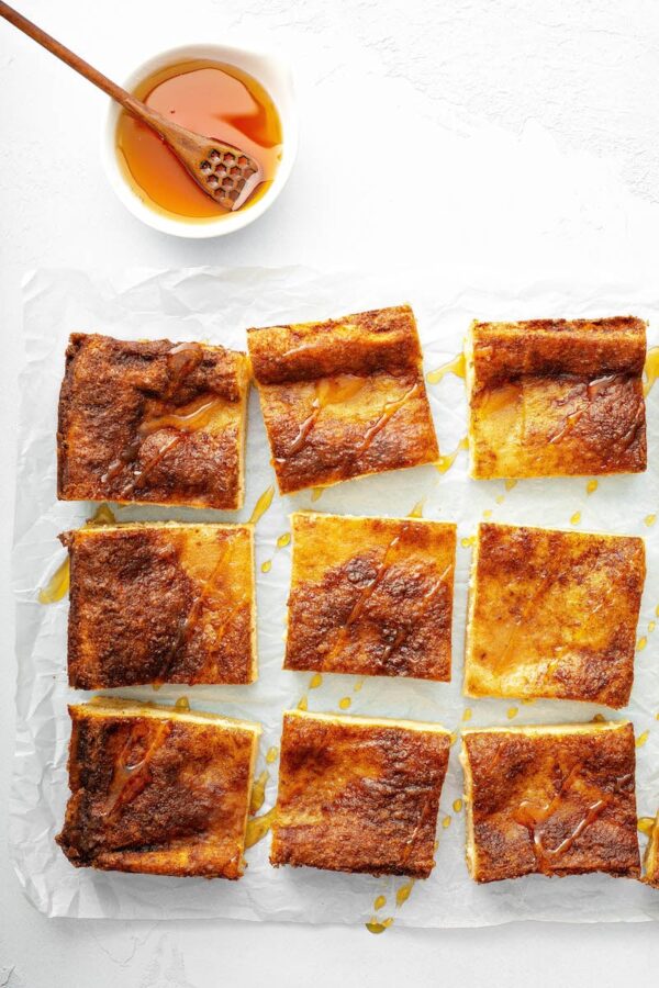 Sopapilla Cheesecake bars sliced into squares with honey on top.