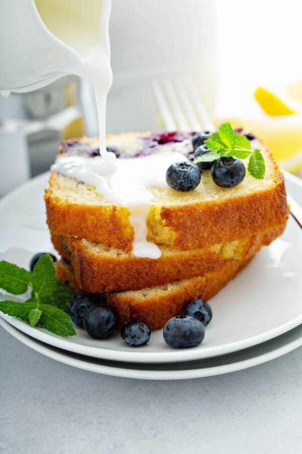 Buttermilk Blueberry Bread slices stacked on top of each other and drizzled with icing.