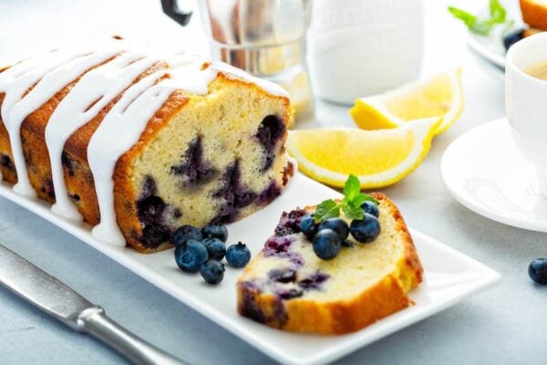 Buttermilk Blueberry Bread drizzled with citrus glaze on a plate.