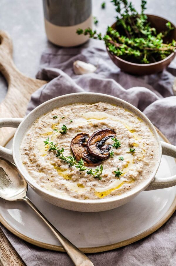 Roasted mushroom soup in a bowl with thyme on top,