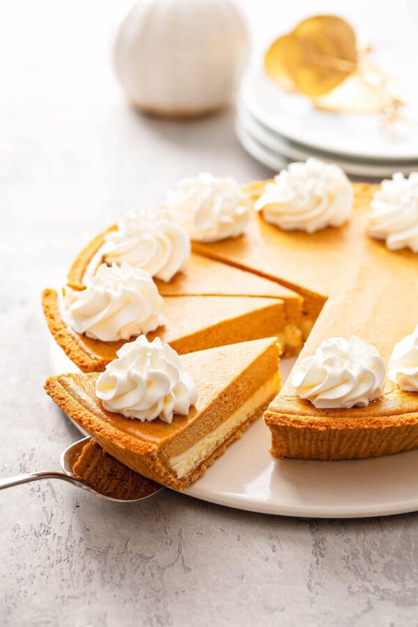 Pumpkin Pie Cheesecake being sliced into pieces with a pie server.