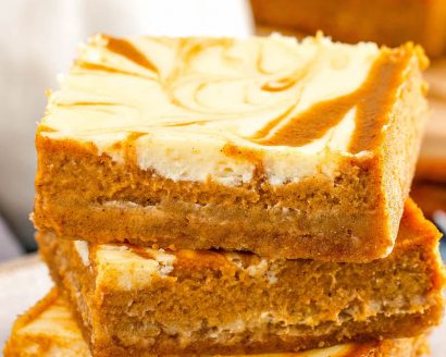 Pumpkin Cheesecake Bars stacked on top of each other.