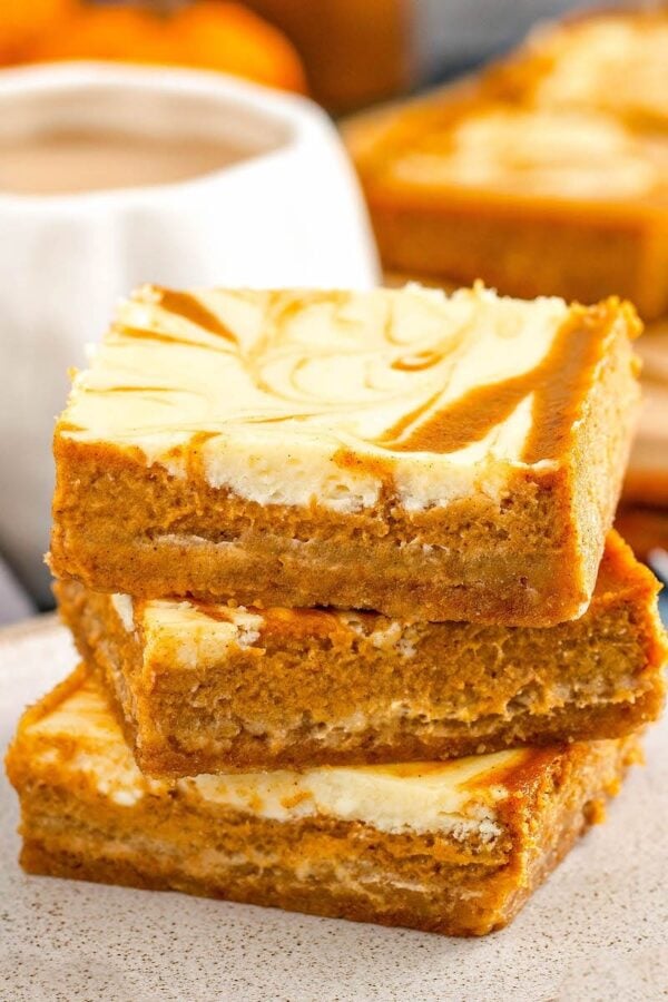 Pumpkin Cheesecake Bars stacked on top of each other.