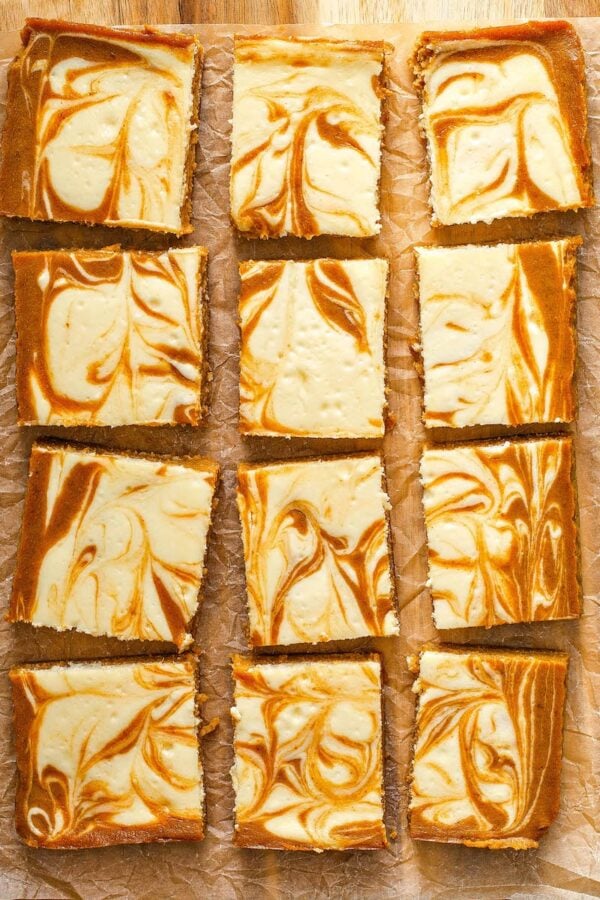 Pumpkin Cheesecake Bars sliced into squares on parchment paper. 