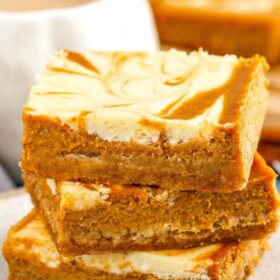 Labeled image of pumpkin cheesecake bars stacked on a plate.