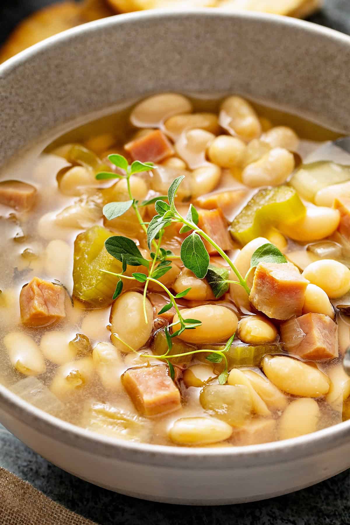 A bowl of ham and bean soup if garnished with fresh herbs.