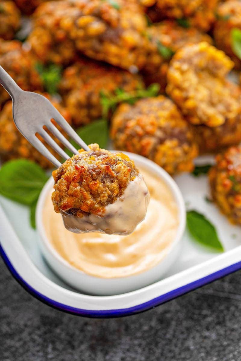 Bisquick Sausage Balls being dipped in sauce.