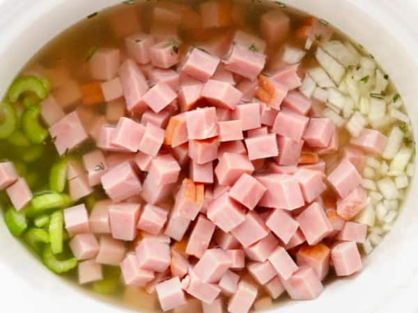 Diced ham is in the crockpot with onions and celery.