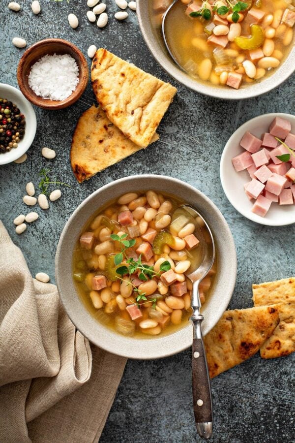 Ham og bønnesuppe i en hvid skål med ekstra skinke.