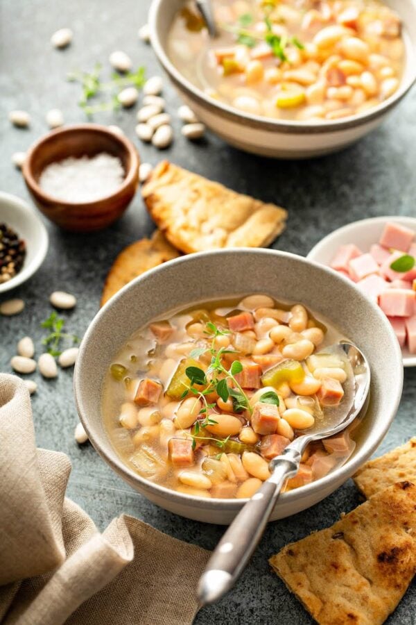 Sopa de jamón y alubias de cocción lenta en un bol con cuchara.