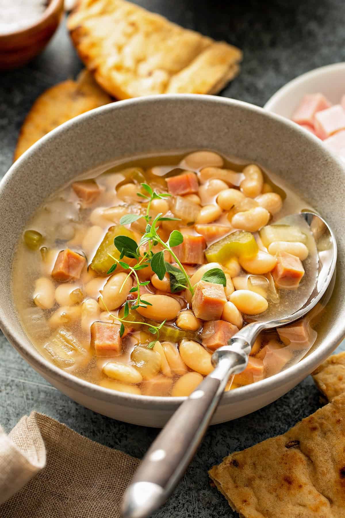 Tender white beans and chunks of ham mixed together in a bowl of warm soup.