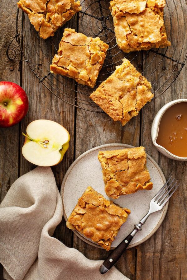 Apple Blondies on a cutting board with fresh apples and caramel.