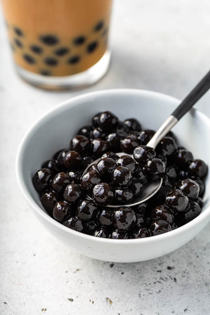 Cooked tapioca pearls in a white bowl with a spoon.