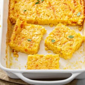 Corn Casserole sliced into squares in a casserole dish.