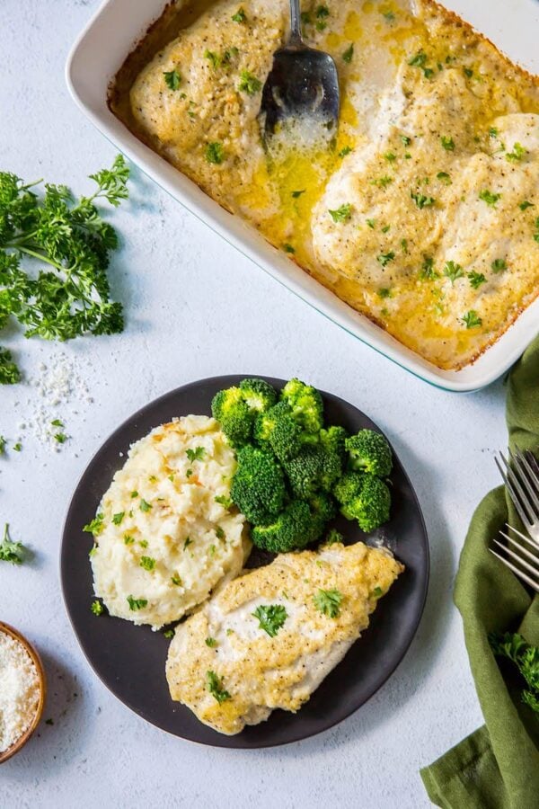 Creamy Parmesan Chicken being scooped out of baking dish and onto a plate.