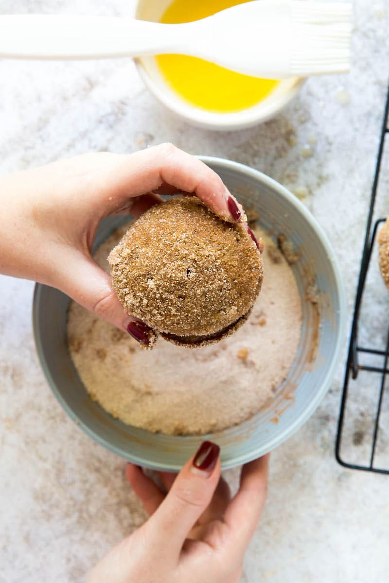 Donut Pumpkin Muffins being tossed in cinnamon sugar coating.