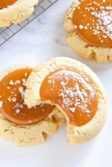 Salted Caramel Cookies topped with flaky sea salt - one cookie has a bite taken out of it.