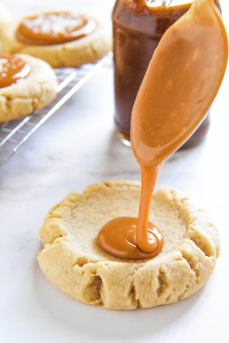 Salted Caramel Cookies with caramel being drizzled inside.