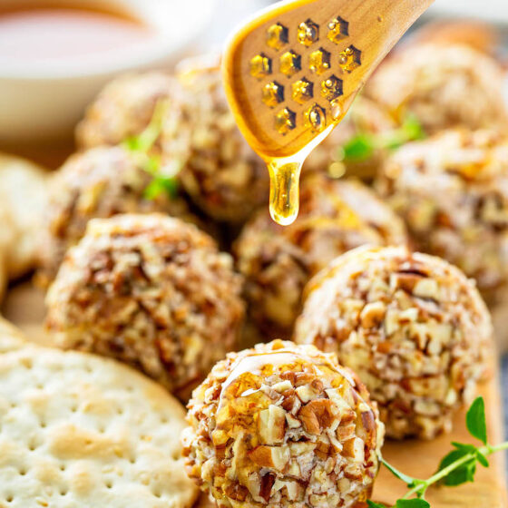 Honey Pecan Cheese Truffles on a platter being drizzled with honey.