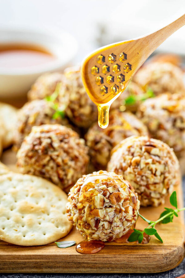 Honey Pecan Cheese Truffles on a platter being drizzled with honey.