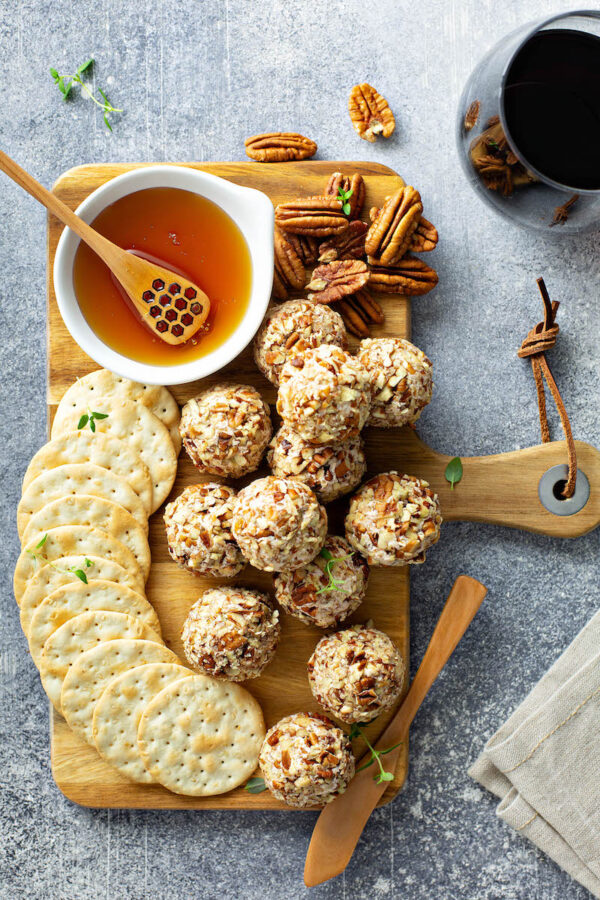 Honey Pecan Cheese Ball on a platter with honey and crackers for a perfect holiday appetizers.