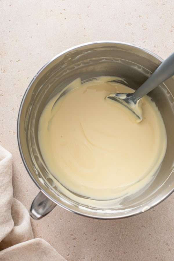 Creamy cheesecake mixture being stirred in a mixing bowl.