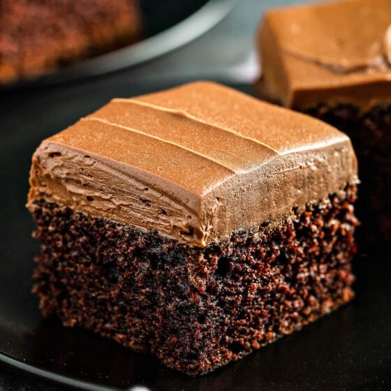 Chocolate Mayonnaise Cake on a black plate with fluffy whipped chocolate icing on top.