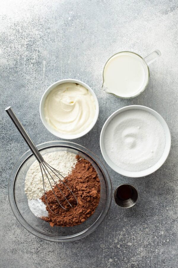 Ingredients in glass bowls with a whisk.