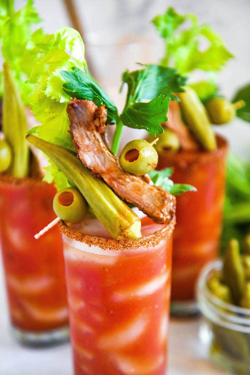 A fully loaded Bloody Mary mix garnished with olives, okra, and a pork rib.