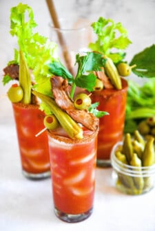 Glasses of Bloody Mary mix topped with custom garnishes like pickled okra, olives, pork ribs and celery stalks.