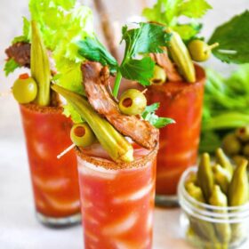 Glasses of Bloody Mary mix topped with custom garnishes like pickled okra, olives, pork ribs and celery stalks.