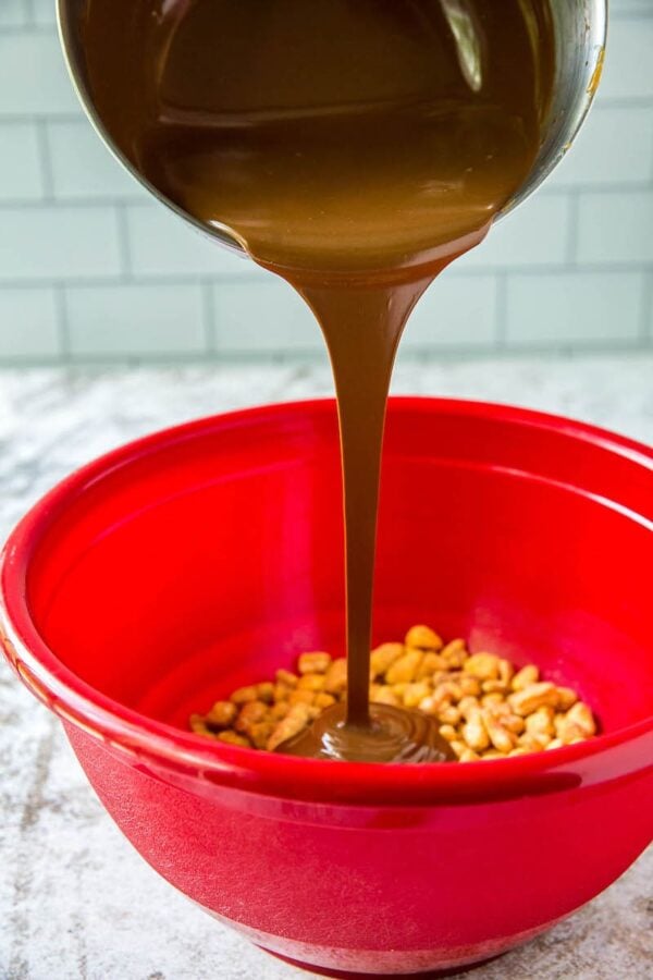 Chocolate and peanut butter are being poured onto of corn pops for Reindeer Poop in a red bowl