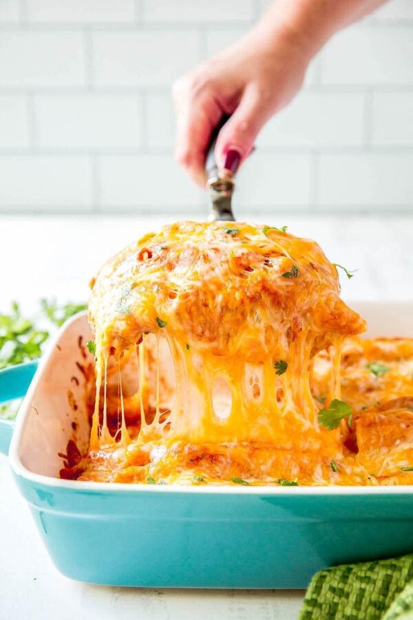 Cheese Enchiladas being pulled out of baking dish with a spatula.