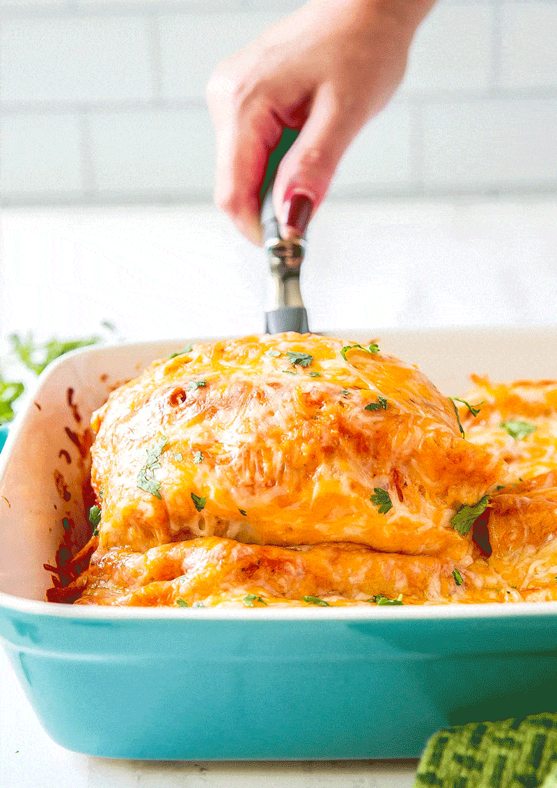 Cheese Enchiladas being pulled up with a spatula to show all the cheesey goodness.