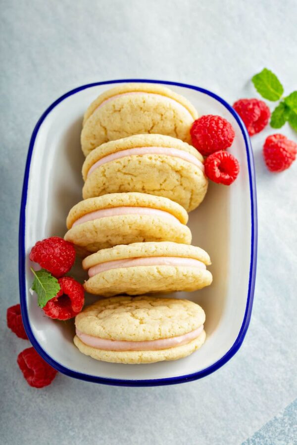 Raspberry Cream Sugar Sandwich Cookie in a white bowl with fresh raspberries