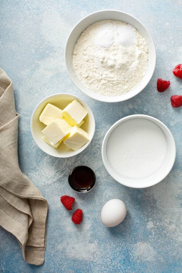 Ingredients for cookies in white bowls with a tea towel. 