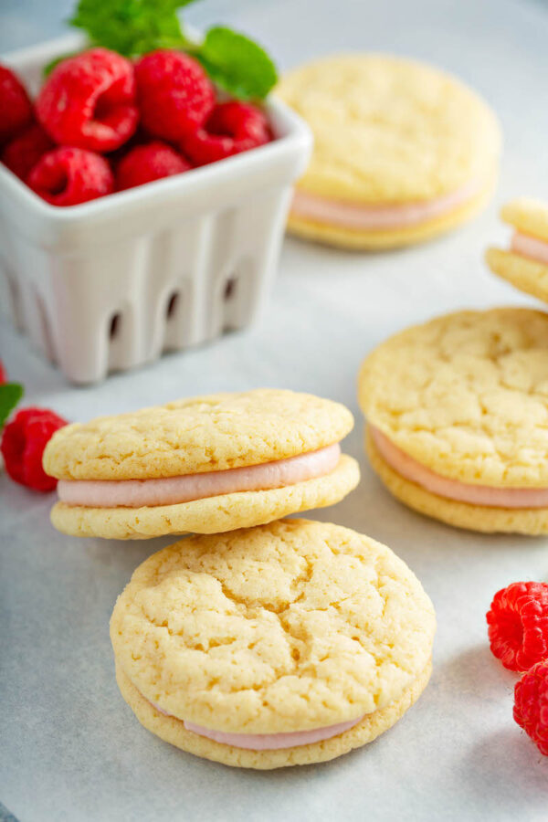 Sandwich Cookies filled with raspberry cream filling stacked on top of each other.