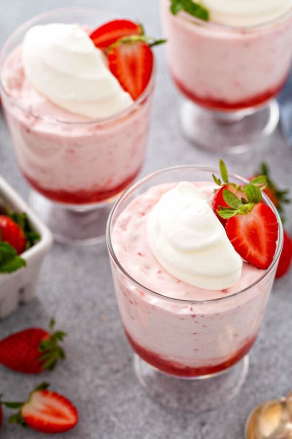 Mousse in a jar with whip cream and strawberries on top.