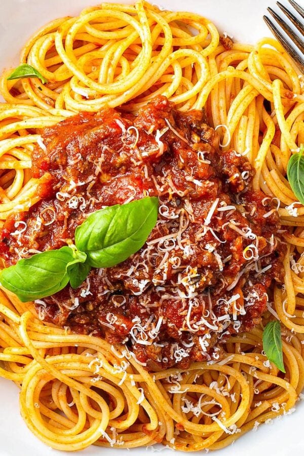 Up close image of bolognese sauce over spaghetti noodles.