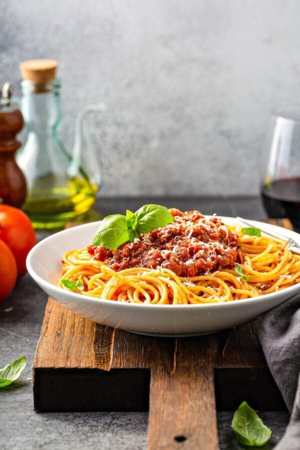 Bolognese sauce over spaghetti in a white bowl.