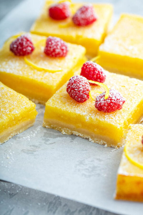 Lemon bars cut into squares on parchment paper. 