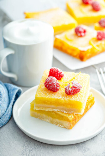 Lemon Bars stacked on a white plate with powdered sugar on top.