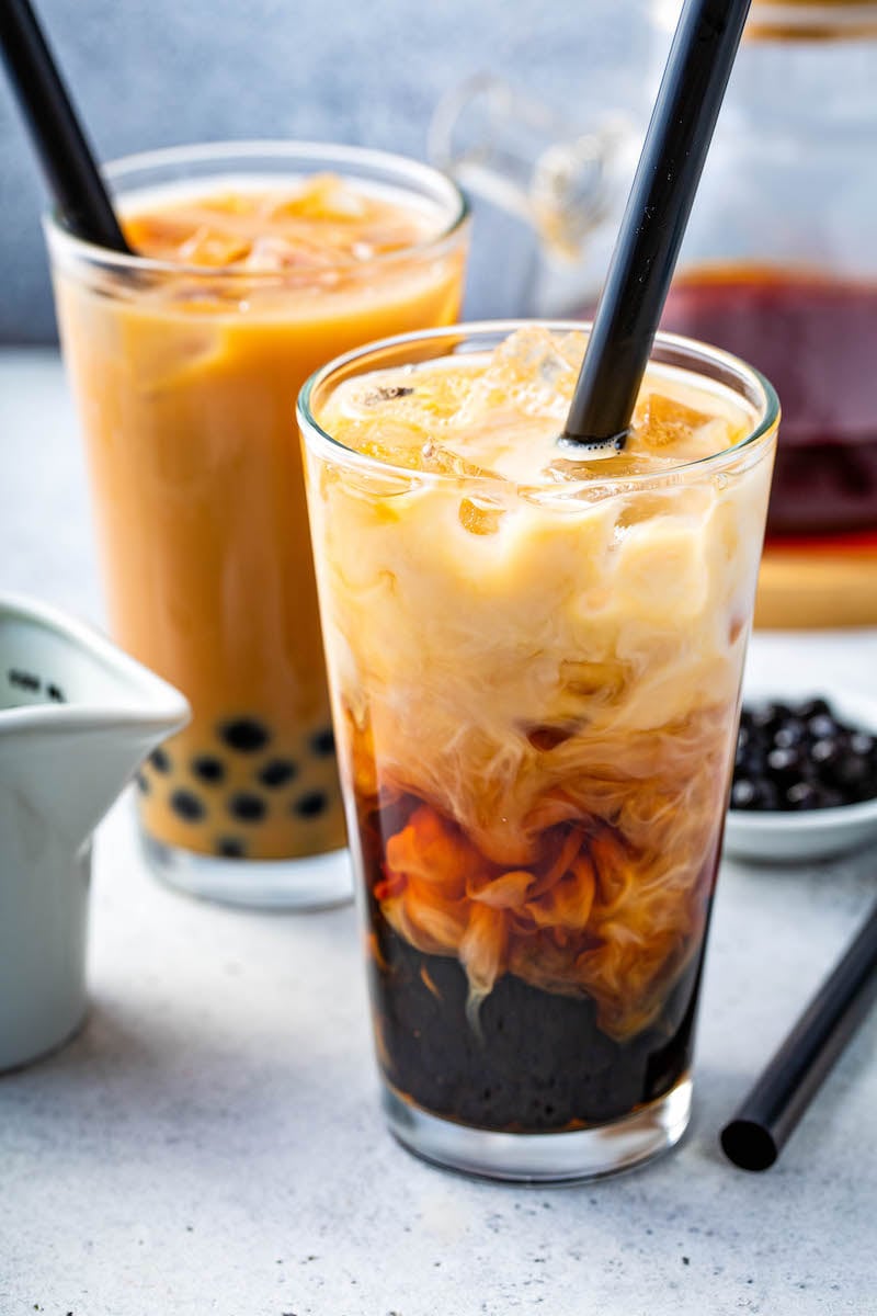 Bubble Tea being mixed together with cream in a glass with ice.