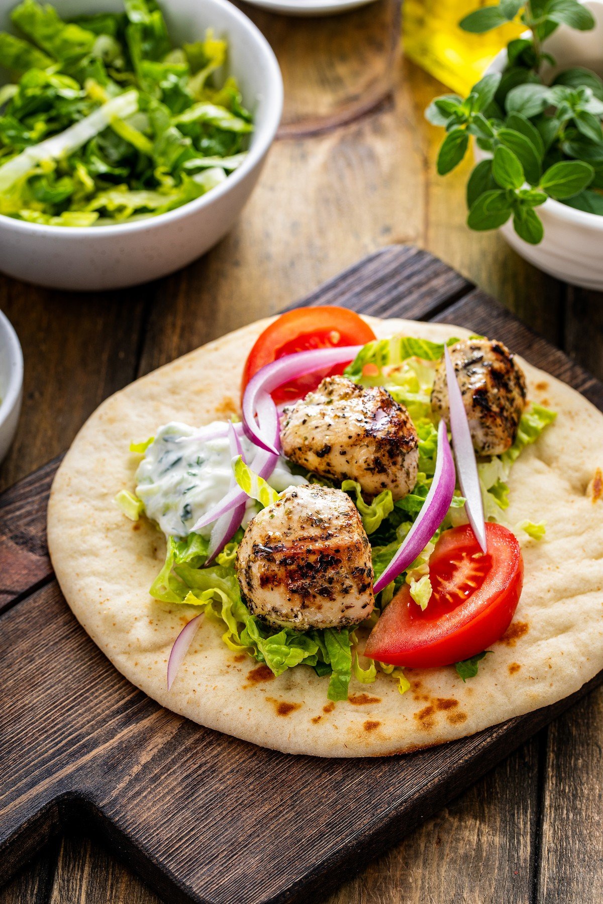 Grilled chicken with fresh tomatoes, lettuce, and red onion on pita bread.