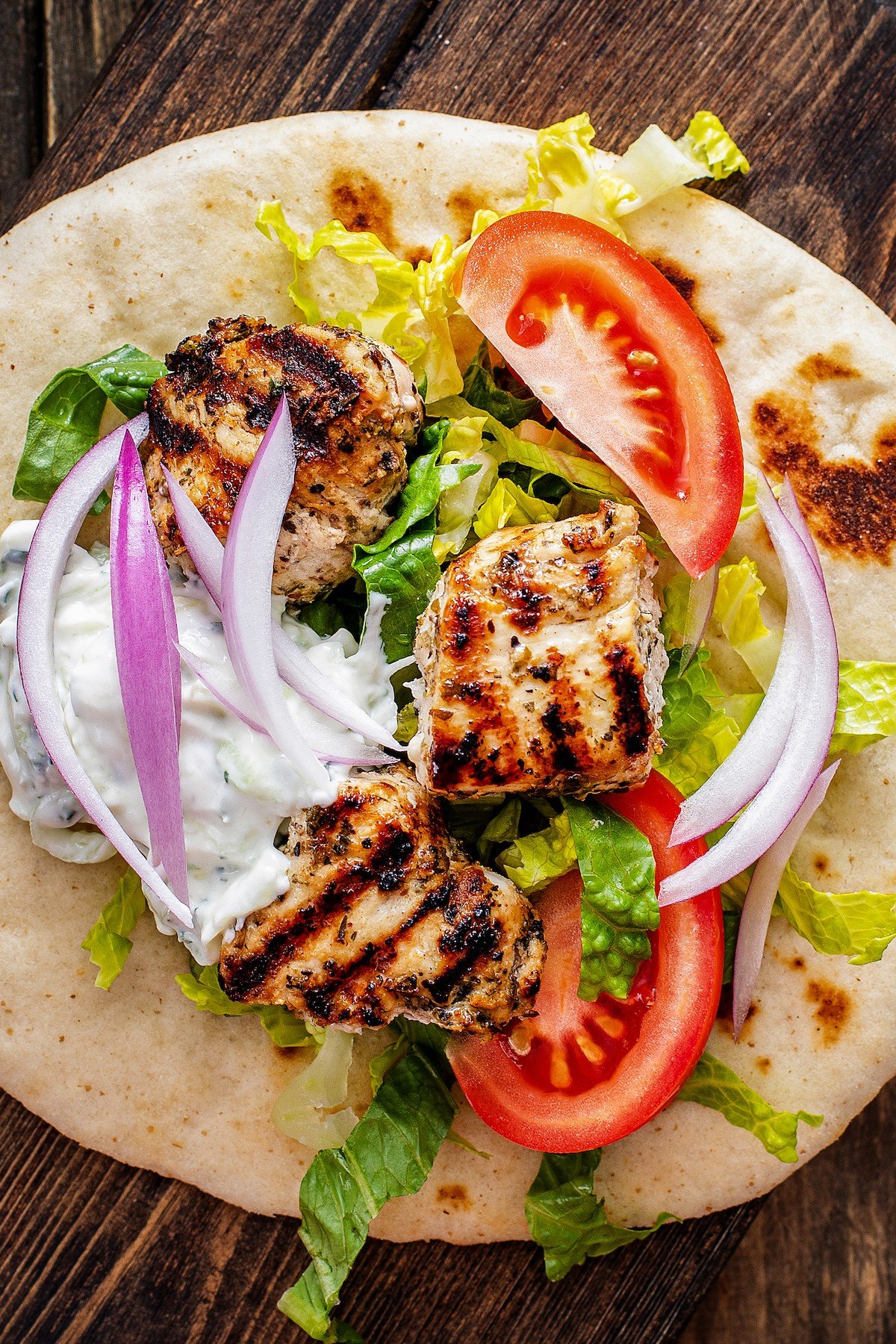 Marinated cooked chicken, tomato wedges, and other fresh veggies on pita bread.