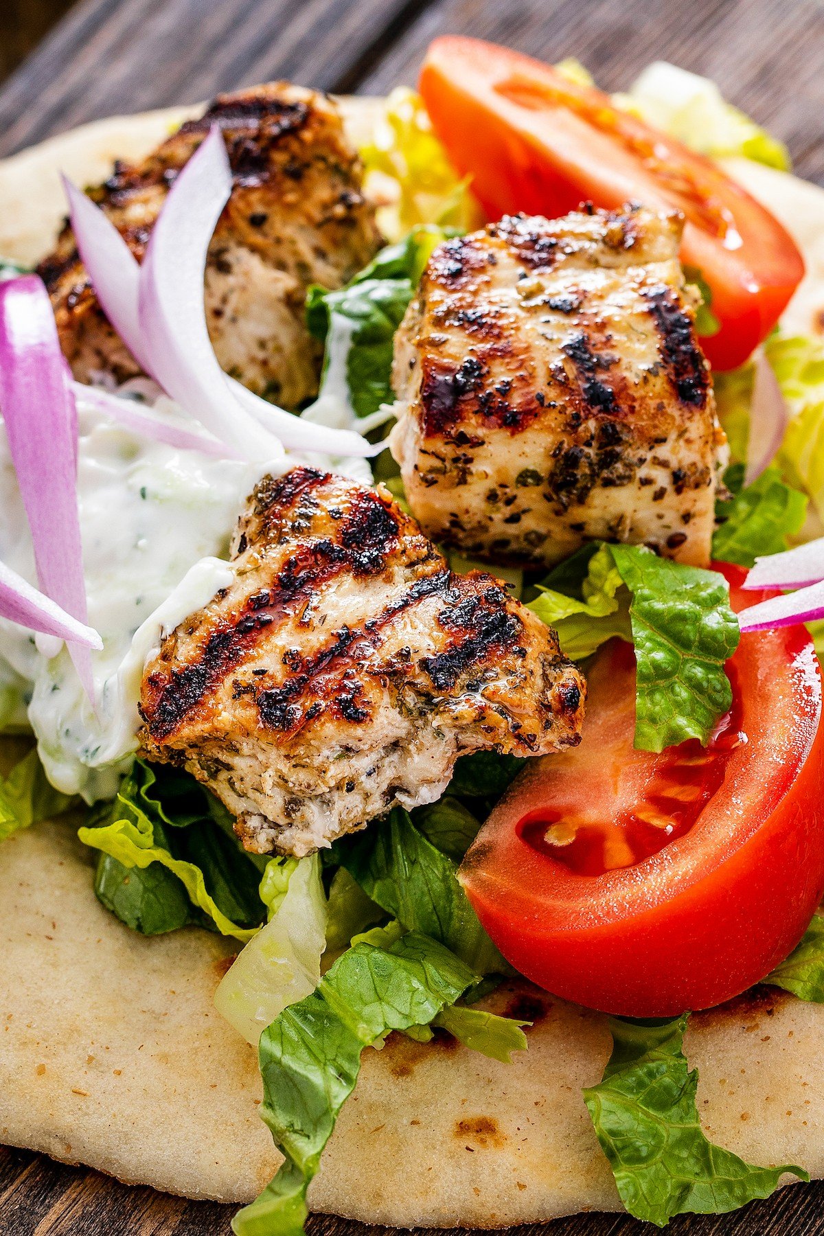 Chicken souvlaki in pita bread with red onion, tomato, lettuce, and tzatziki sauce.