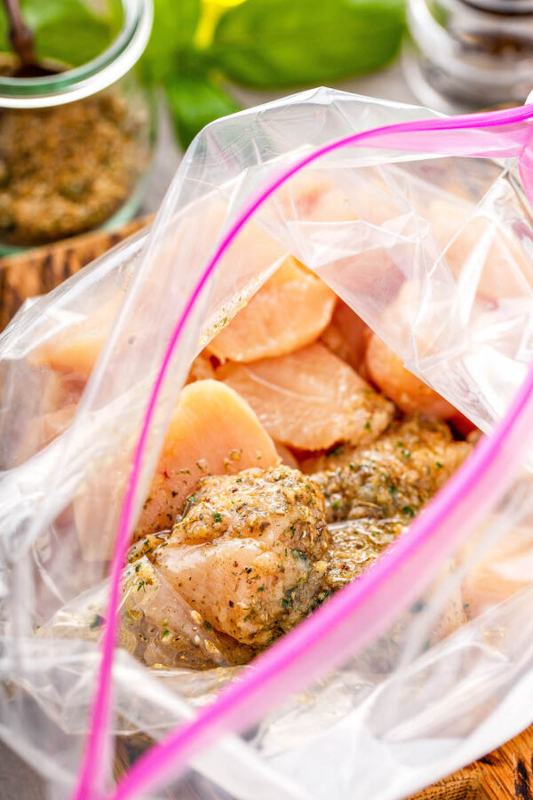 Top view of a ziploc bag with raw chicken breasts and spices