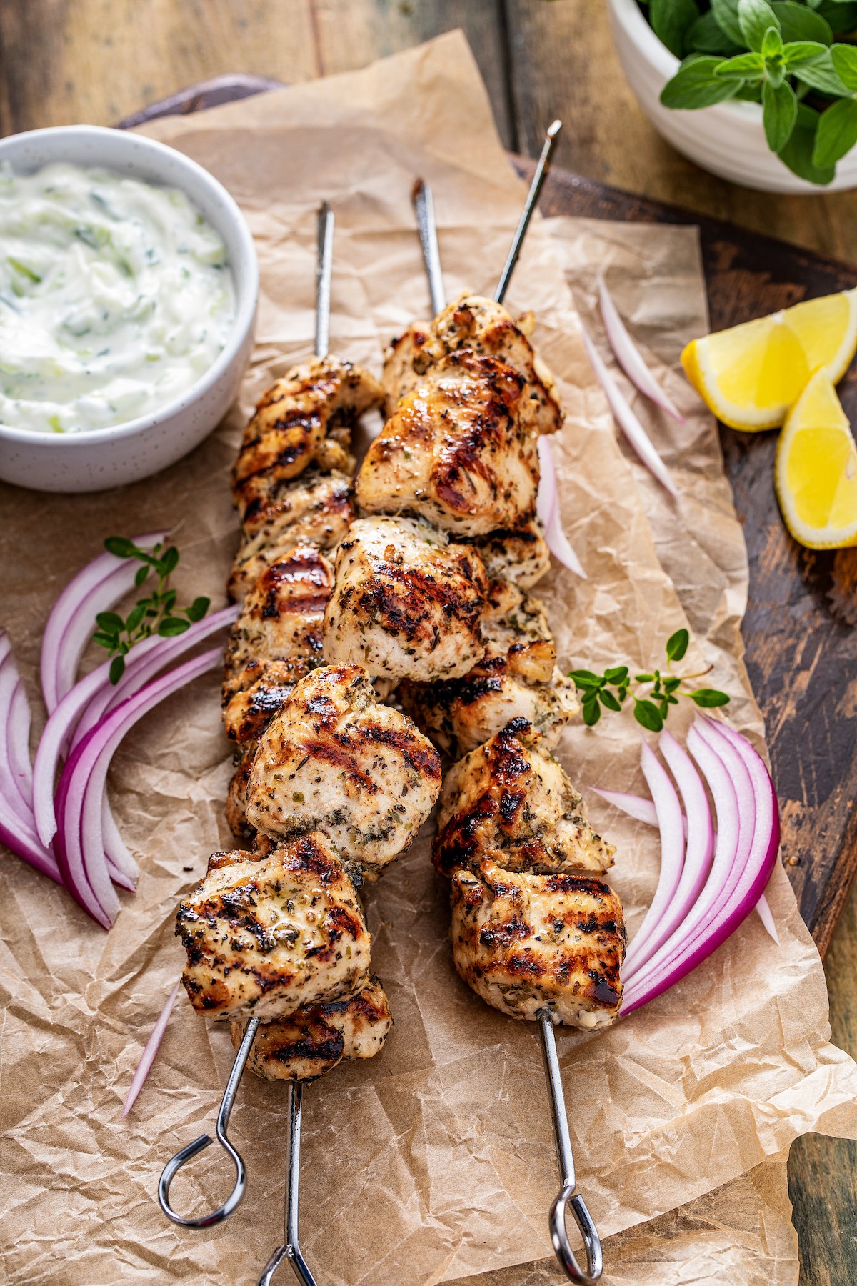 Grilled chicken on skewers next to red onion.