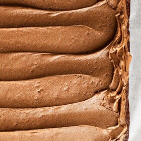 Swirls of homemade chocolate buttercream frosting spread on top of a chocolate cake.