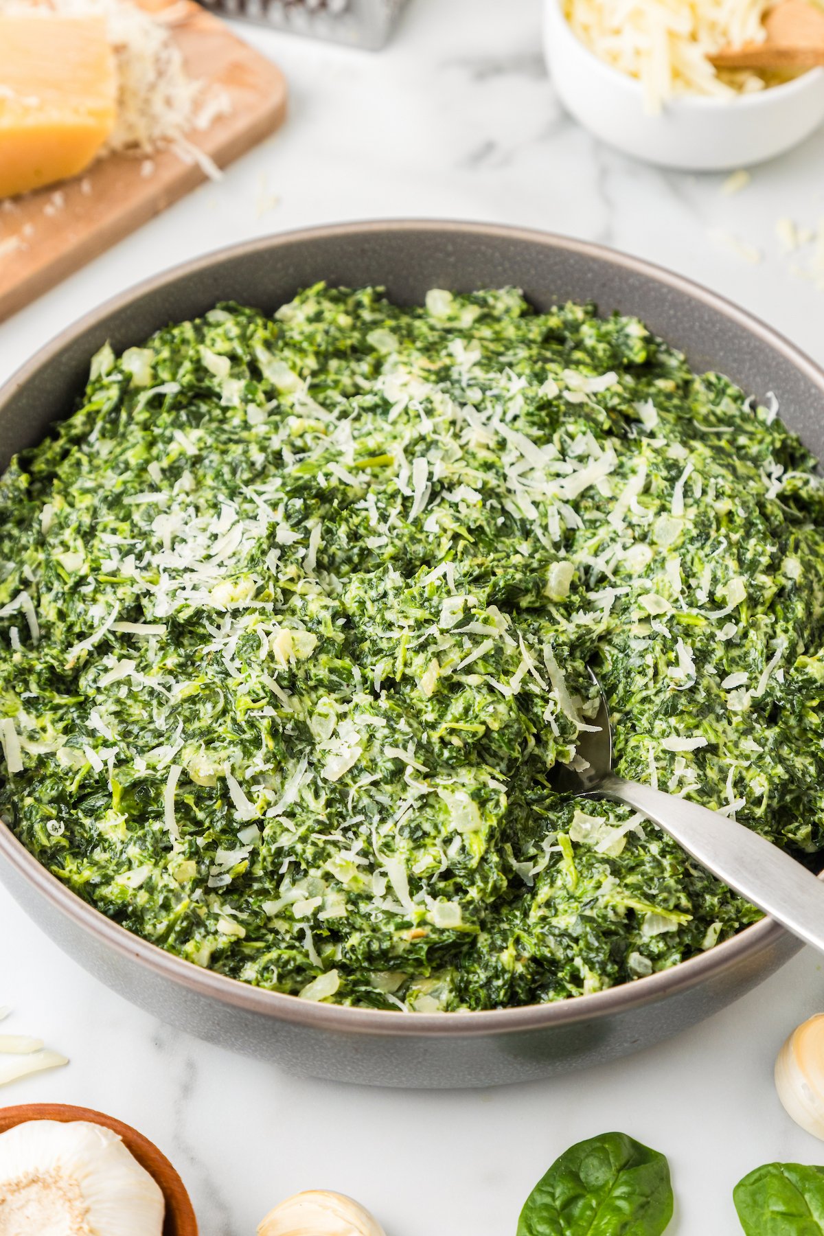 Creamed spinach in a skillet with freshly grated parmesan on top. 